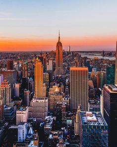 new york city skyline at sunset with the empire building in the foreground and other tall buildings