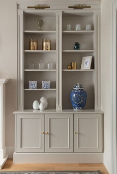 a white and blue vase sitting on top of a wooden shelf next to a fireplace