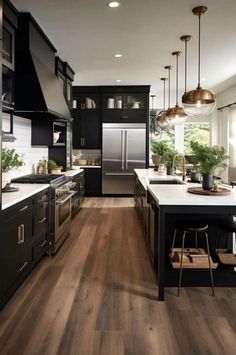 a large kitchen with black cabinets and white counter tops, wood flooring and stainless steel appliances