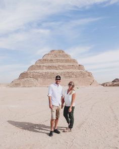 two people standing in front of a pyramid