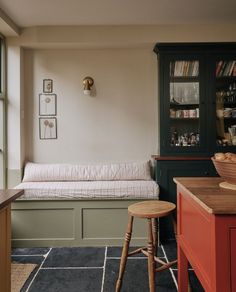 a kitchen with a bench, counter and cabinets in it's center area next to a window