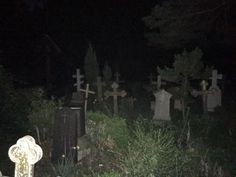 a cemetery at night with tombstones in the foreground