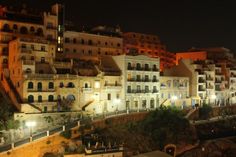 the city is lit up at night with many buildings on it's hillsides