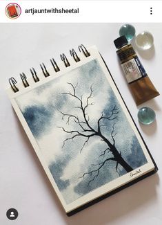 an art journal with watercolors and paintbrushes next to it