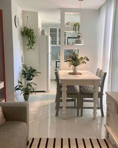 a living room and dining area with white tile flooring in the center, plants on the table