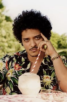 a man sitting at a table with a straw in his hand and looking off to the side