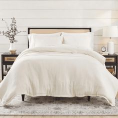 a bed with white sheets and pillows in a room