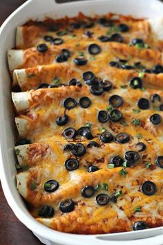 a white casserole dish filled with black olives and cheesy bread