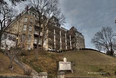 an old building with stairs leading up to it and a sign on the hill in front