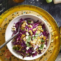 a bowl filled with coleslaw and corn on top of a yellow plate