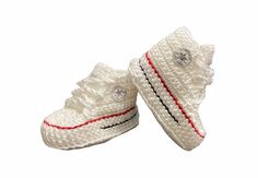 two crocheted white shoes with red trims