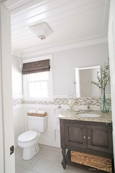 a bathroom with a toilet, sink and mirror