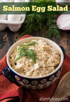 an egg salad in a blue and white bowl on a red napkin next to sliced onions