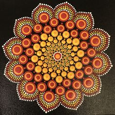 a painting with circles and dots in the center on a black tablecloth, depicting an orange flower