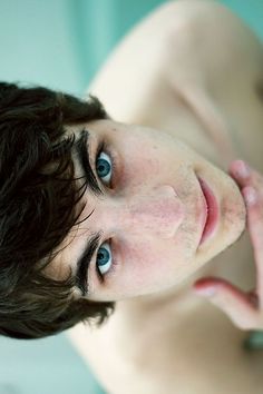 a close up of a young man with short hair and blue eyes looking at the camera