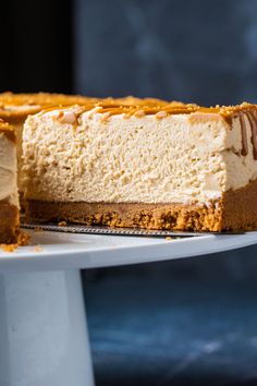 a cheesecake on a white cake plate with one slice cut out and ready to be eaten