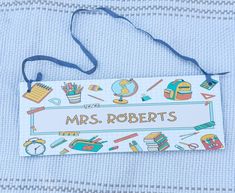 a name tag with school items on it sitting on top of a blue bed sheet