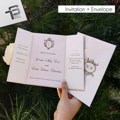 a person holding an open wedding card in front of some pine branches with the words,'celebration + envelope'written on it