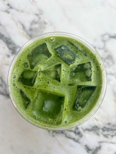 a green drink with ice cubes in it