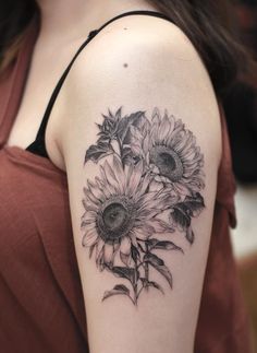 a woman's arm with sunflowers tattooed on the back of her shoulder