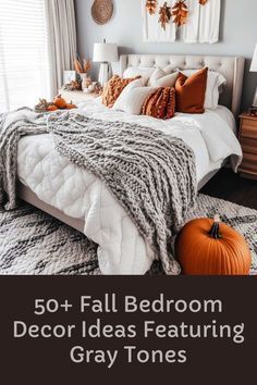 a bedroom decorated in fall colors with white and orange pillows, gray bedding, and pumpkins