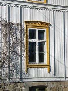 an old white building with a yellow window