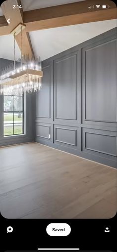 an empty room with gray walls and chandelier