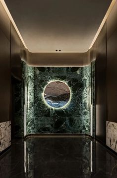 an empty room with marble walls and flooring, along with a circular mirror on the wall