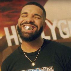 a man with piercings standing in front of a sign and smiling at the camera