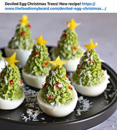 deviled eggs decorated with christmas trees are on a black platter and have yellow stars