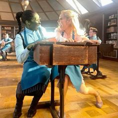 two people sitting at a desk in front of bookshelves