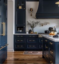 a kitchen with dark blue cabinets and gold pulls on the door handles, along with white marble countertops