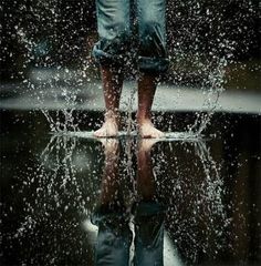 a person standing in the rain with their feet up and water splashing on them