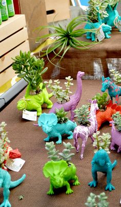 there are many toy dinosaurs on the table with succulents and air plants