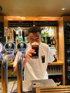 a man holding up a beer in front of a bar