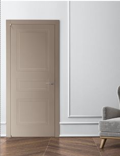 an empty room with a gray chair and beige door in the corner, next to a white wall