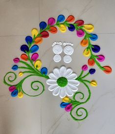 an artistically decorated wall hanging with flowers and swirls in the center, on a white tile floor