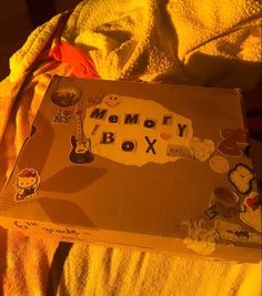 an open memory box sitting on top of a bed covered in yellow sheets and blankets