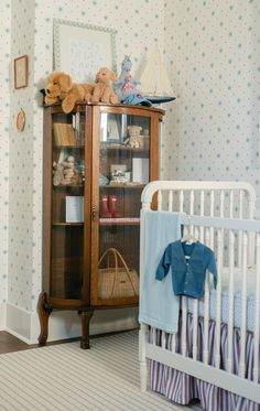 a baby's room with a crib, dresser and teddy bear on the wall