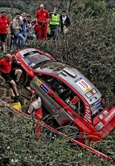 a rally car that is stuck in the mud with people looking on from behind it