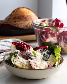 a bowl filled with salad next to a loaf of bread