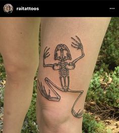 a woman's leg with a skeleton tattoo on it and two hands in the shape of a frog