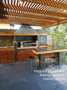 an outdoor kitchen with grill and bar stools