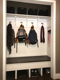 a white bench with several hats and scarves hanging from it's back wall