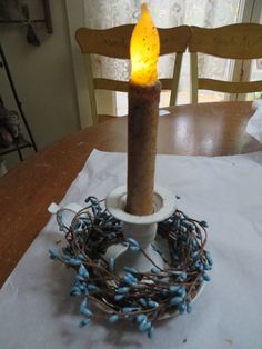 a lit candle sitting on top of a table next to a bird's nest