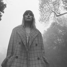 a woman standing in the fog wearing a coat