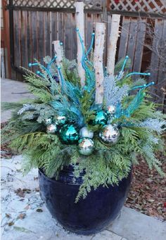 a potted plant with blue and green ornaments on it's side in the snow