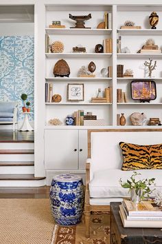 a living room filled with furniture and bookshelves next to a stair case covered in pictures