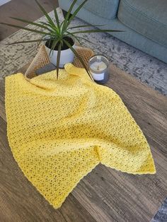 a potted plant sitting on top of a wooden floor next to a yellow blanket