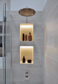 a bathroom with two shelves above the toilet and shower head mounted to the side of the wall